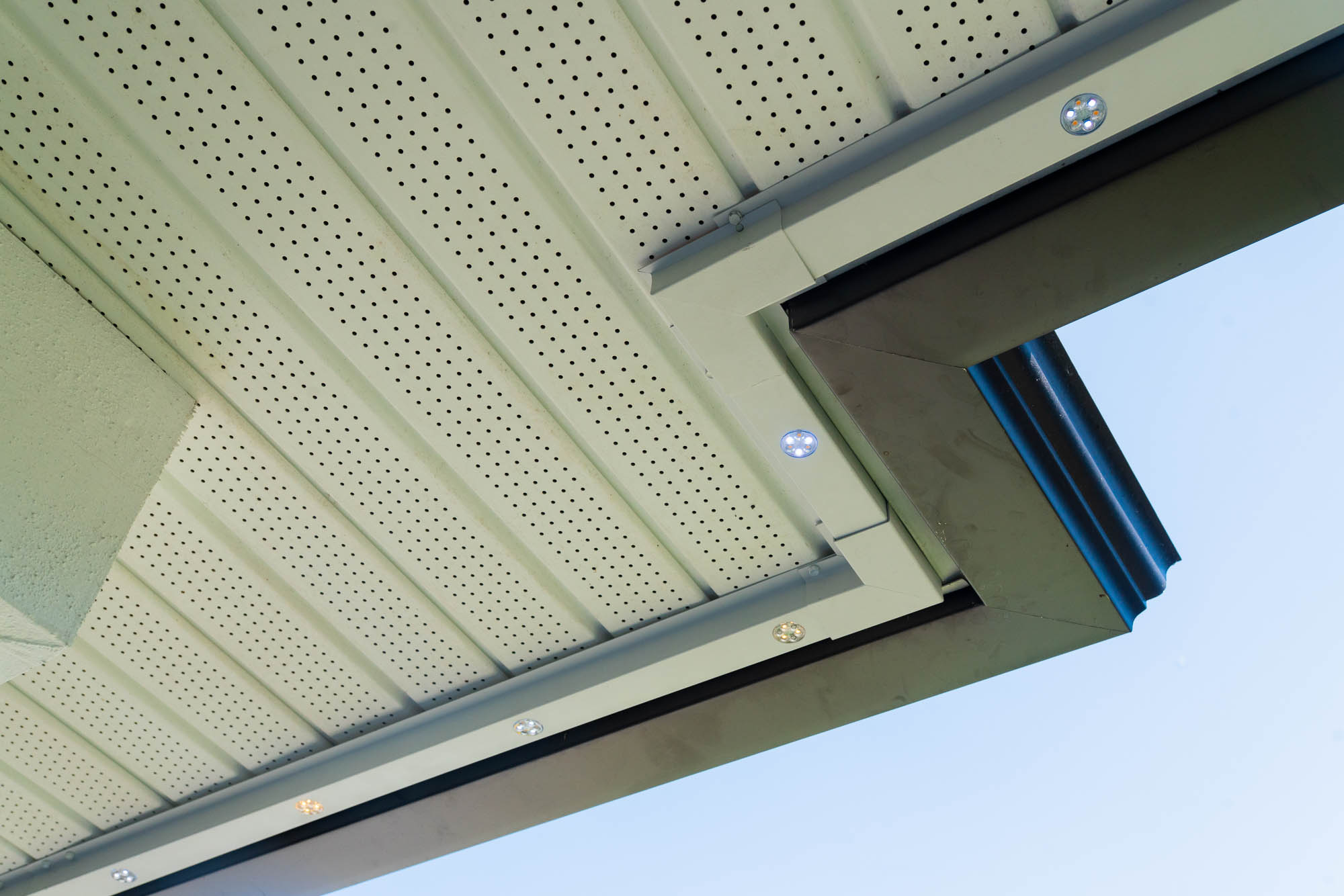 Low-profile permanent LED light track flush against a white soffit in daylight